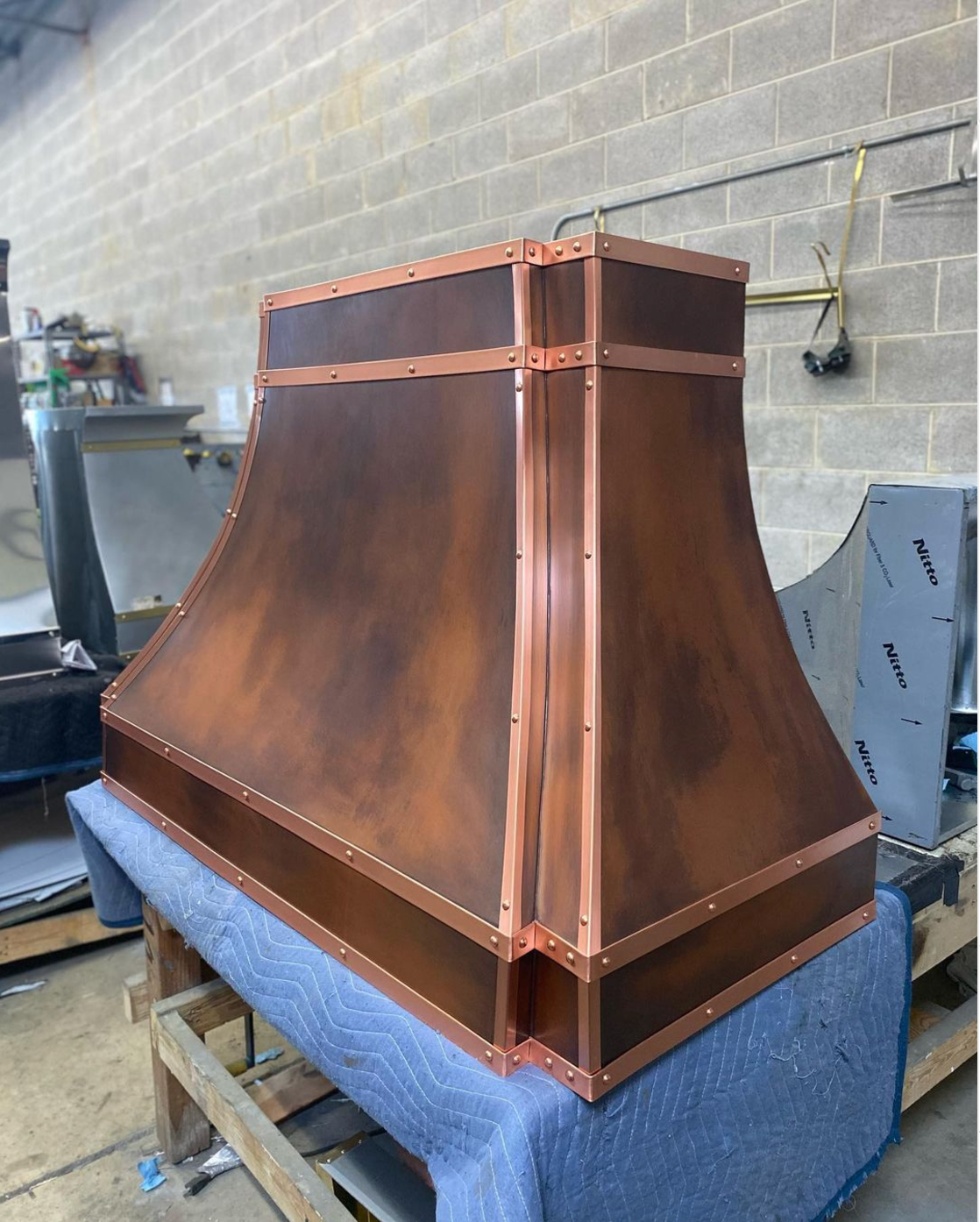A large copper hood is sitting on top of a wooden table.