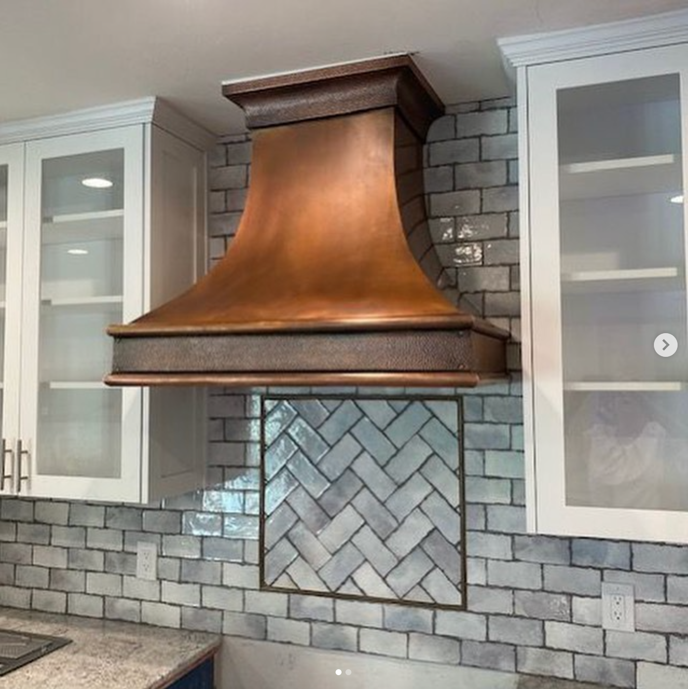 A kitchen with a copper hood hanging from the ceiling