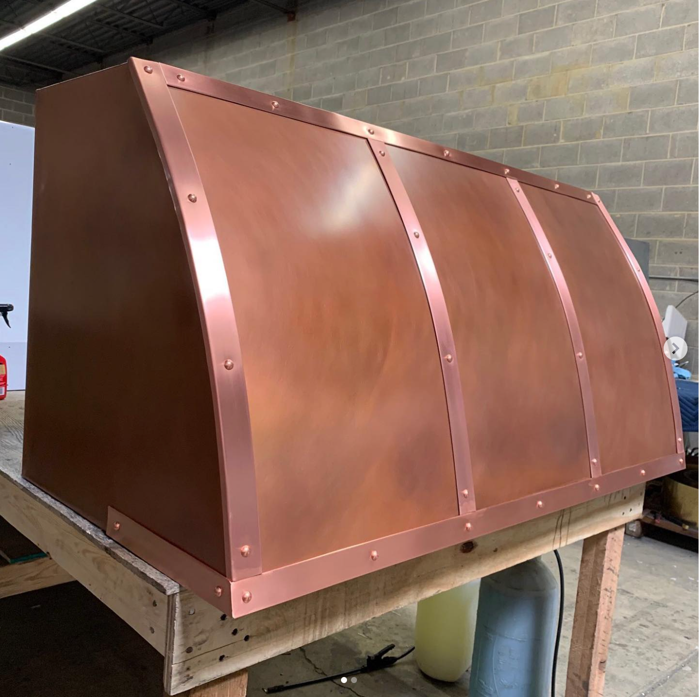 A copper hood is sitting on top of a wooden table.