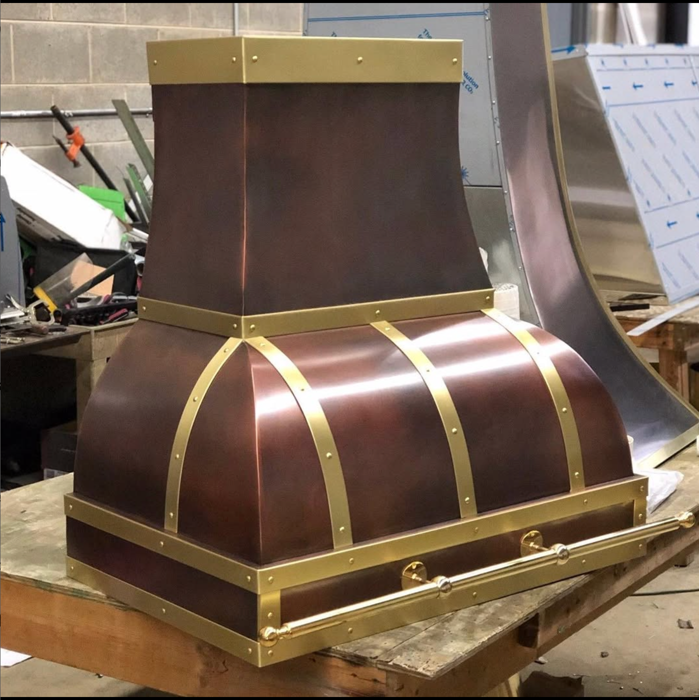 A copper hood with gold trim sits on a wooden table