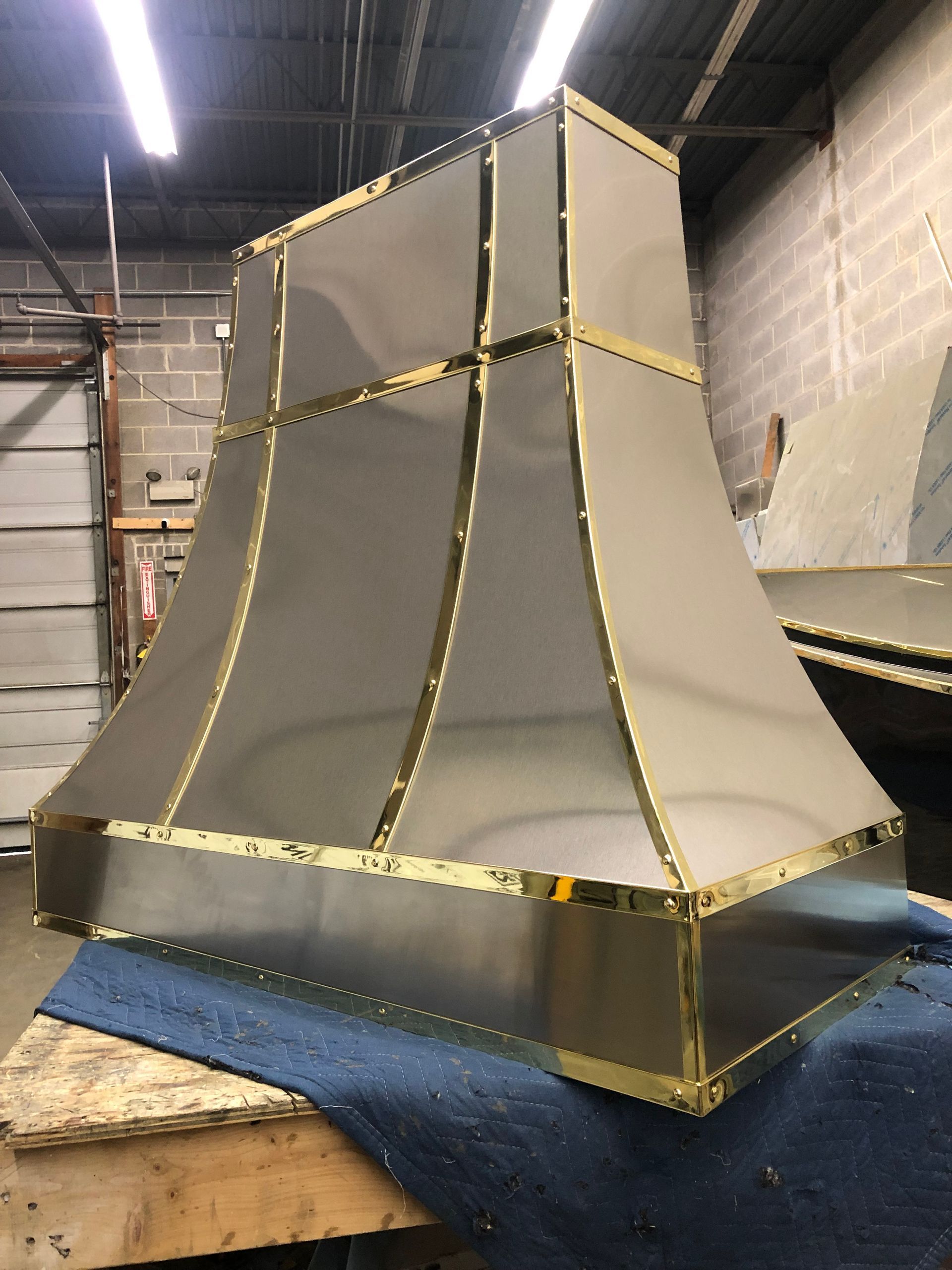 A stainless steel hood with gold trim sits on a table