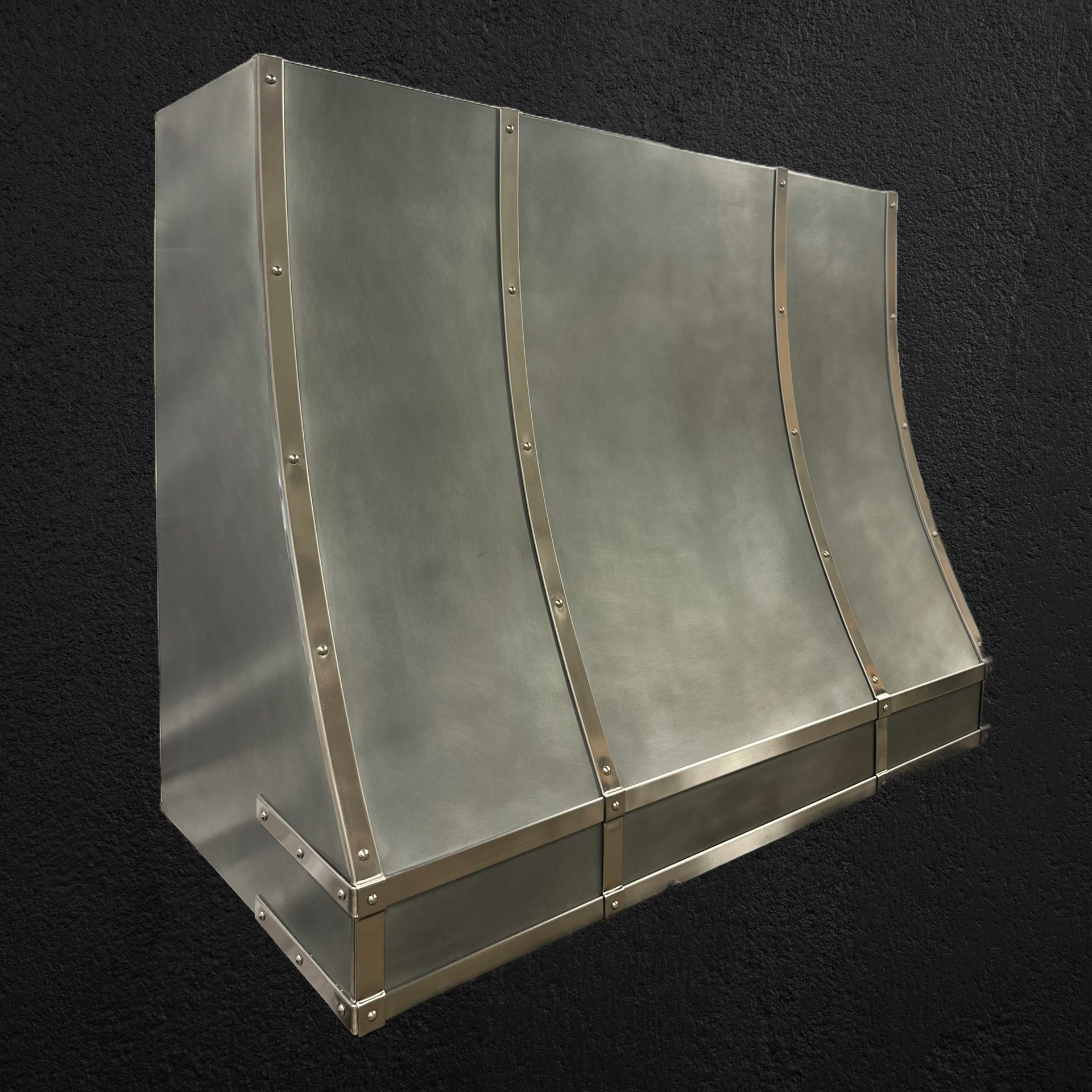 A stainless steel hood is sitting on a black surface.