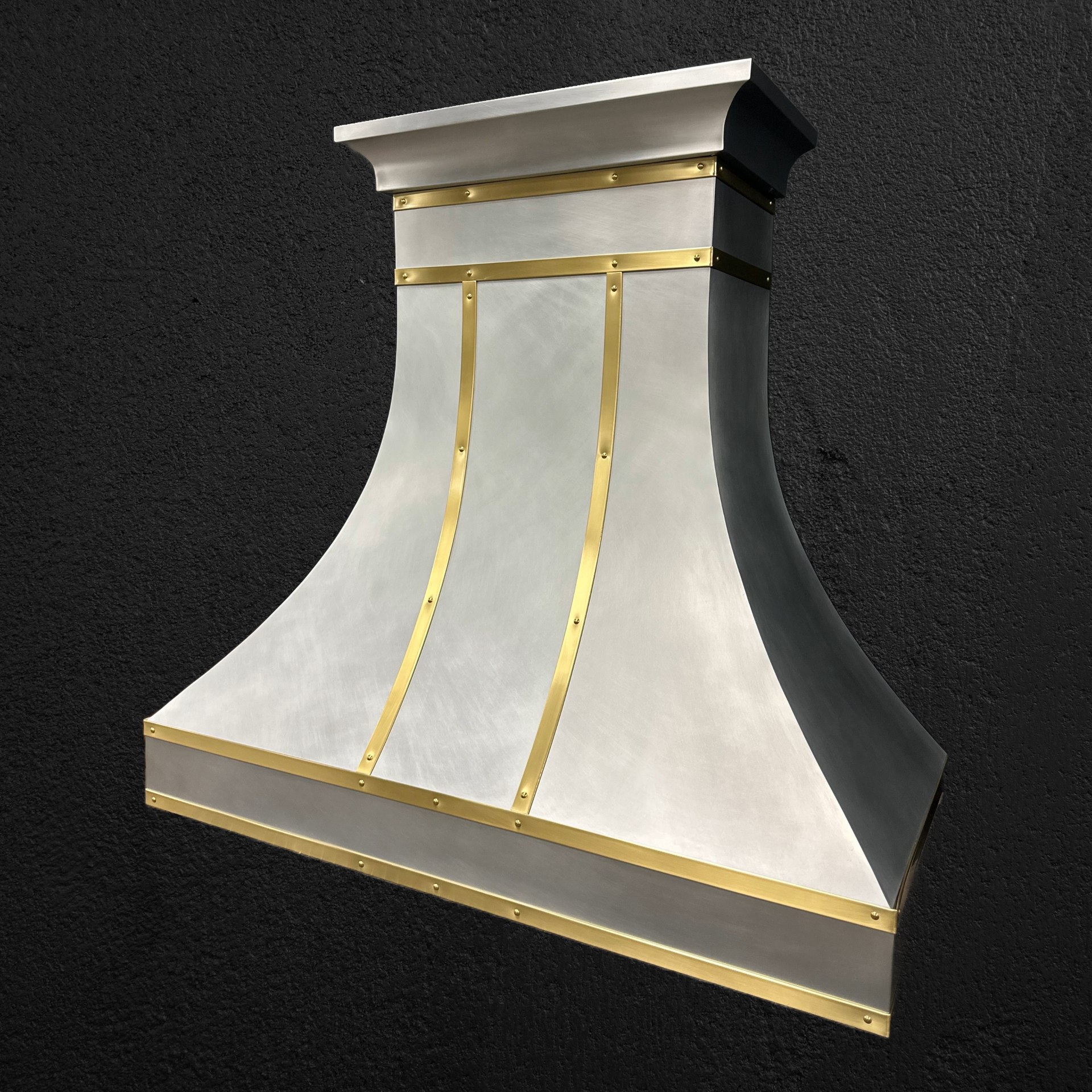 A stainless steel hood with gold trim sits on a black surface