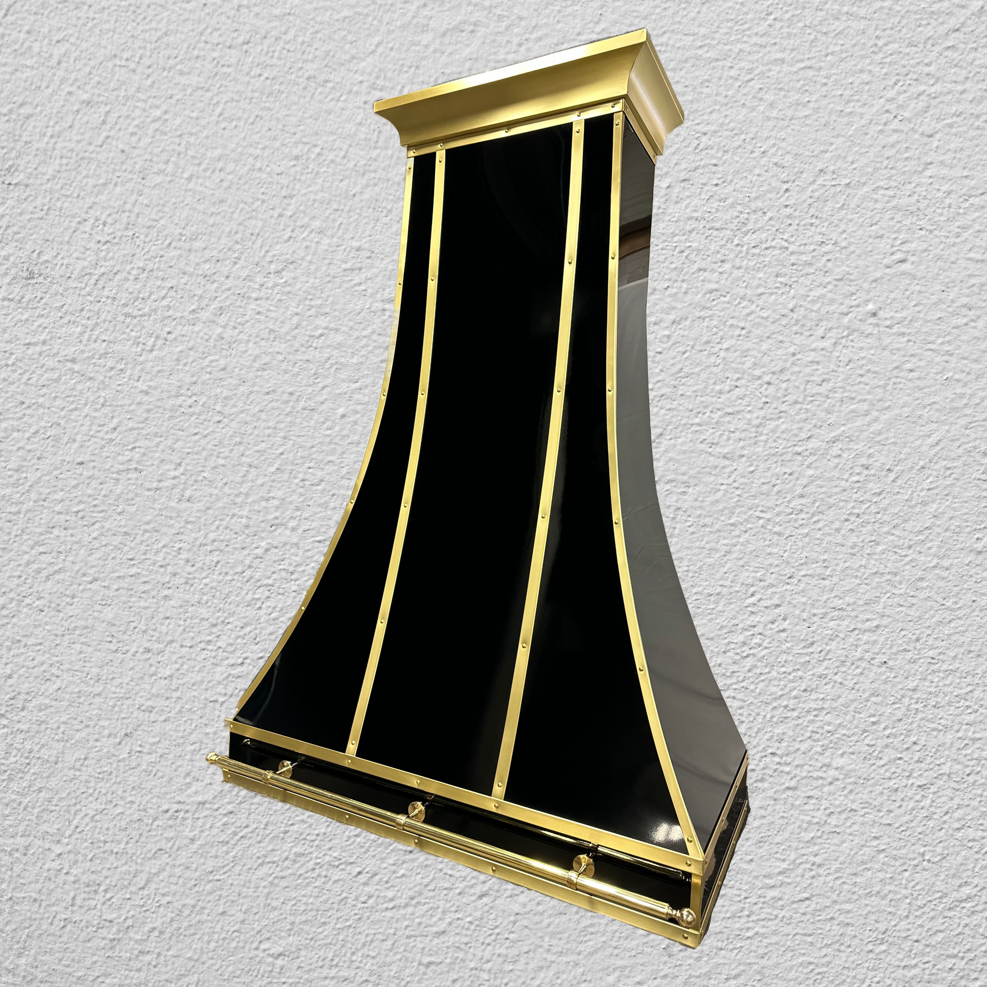A black and gold item is against a white wall