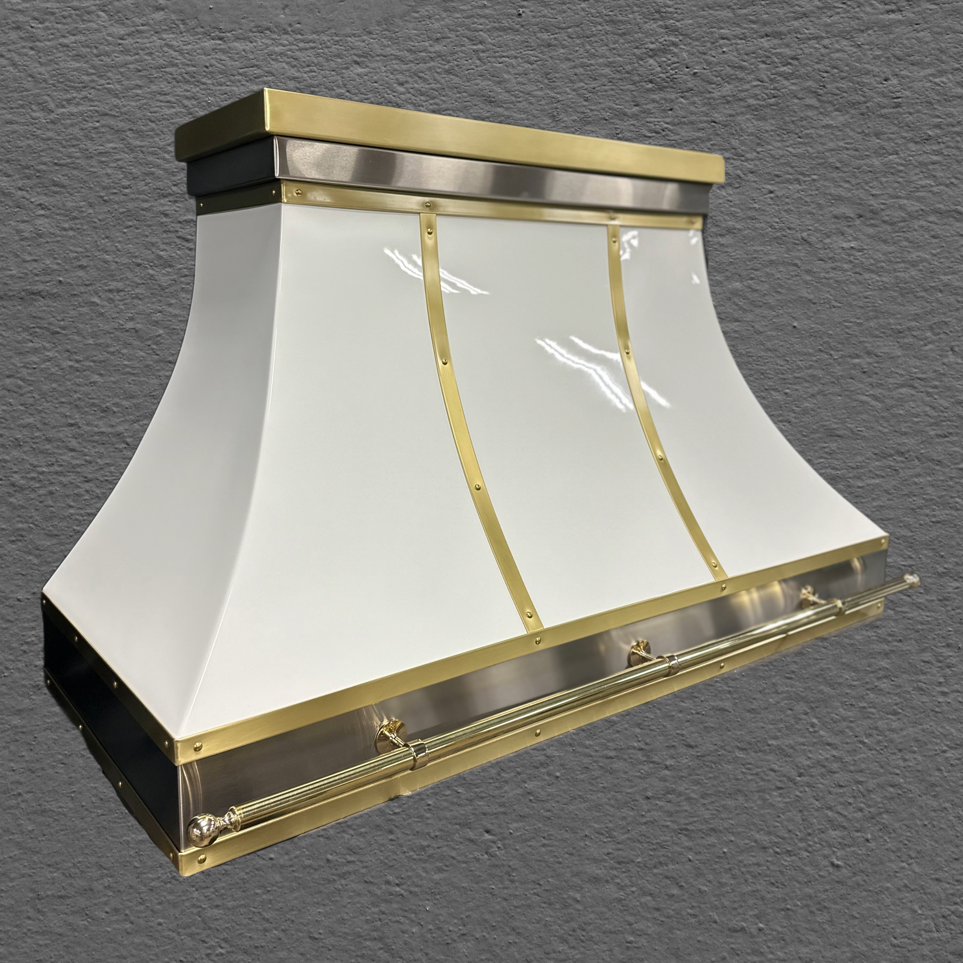 A white hood with brass trim is sitting on a gray surface.