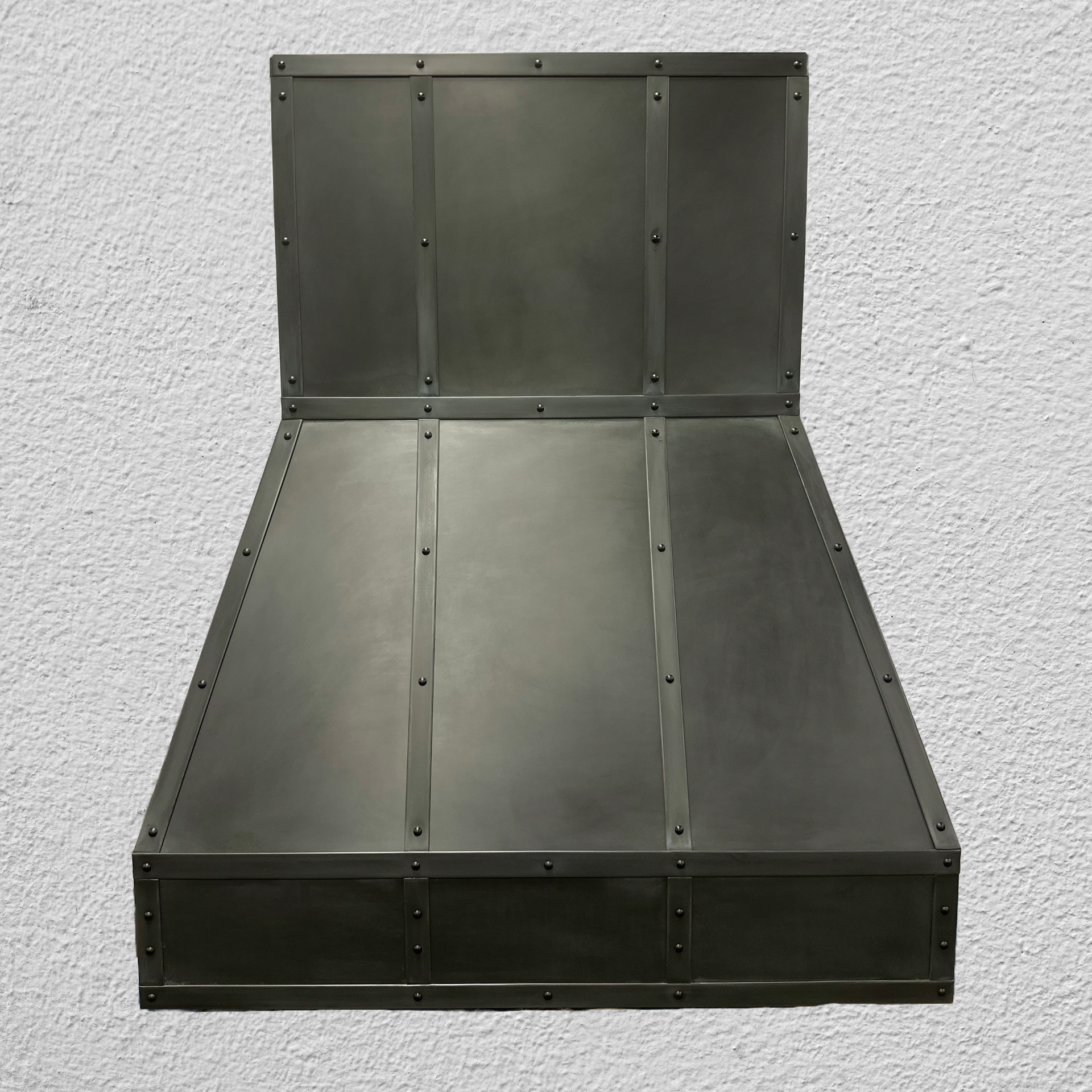 A black metal item is against a white wall