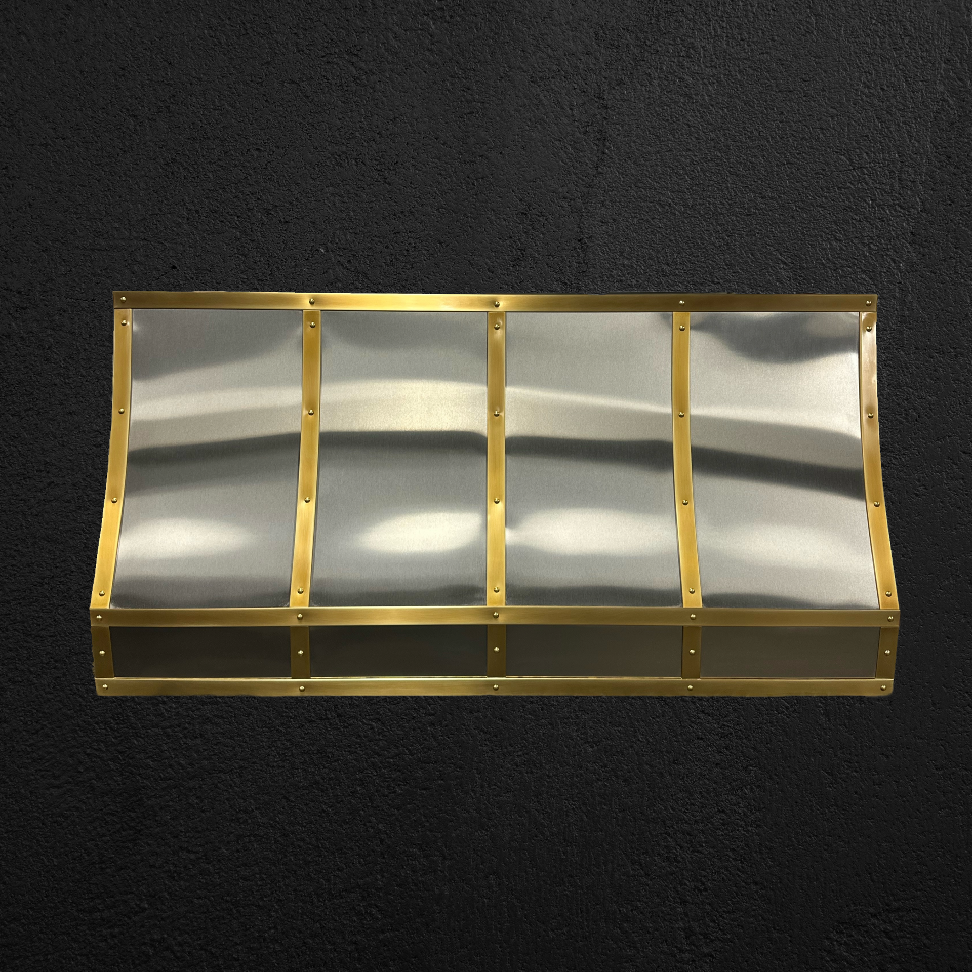 A stainless steel awning with brass trim is sitting on a black surface.