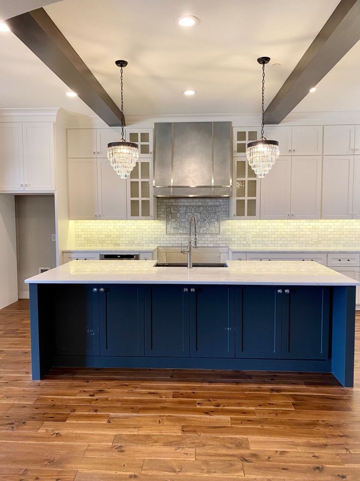 A kitchen with blue cabinets , white cabinets , and a large island.