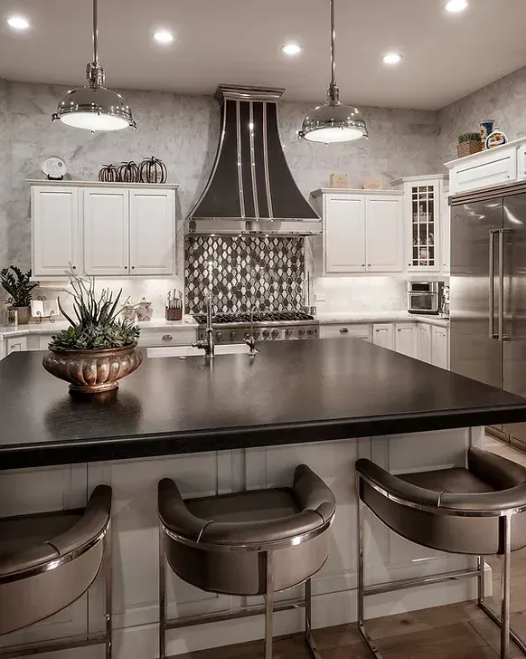 A kitchen with a large island , stools and a stove.