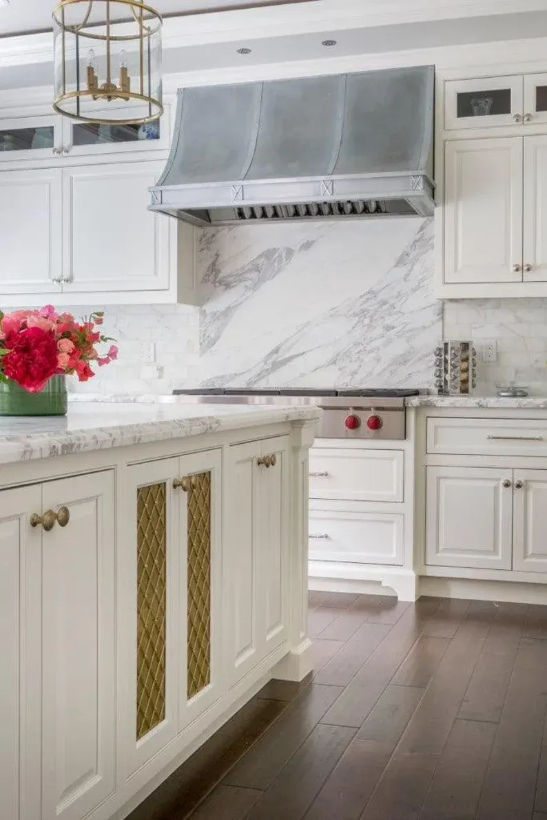 A kitchen with white cabinets , a stove , and a hood.