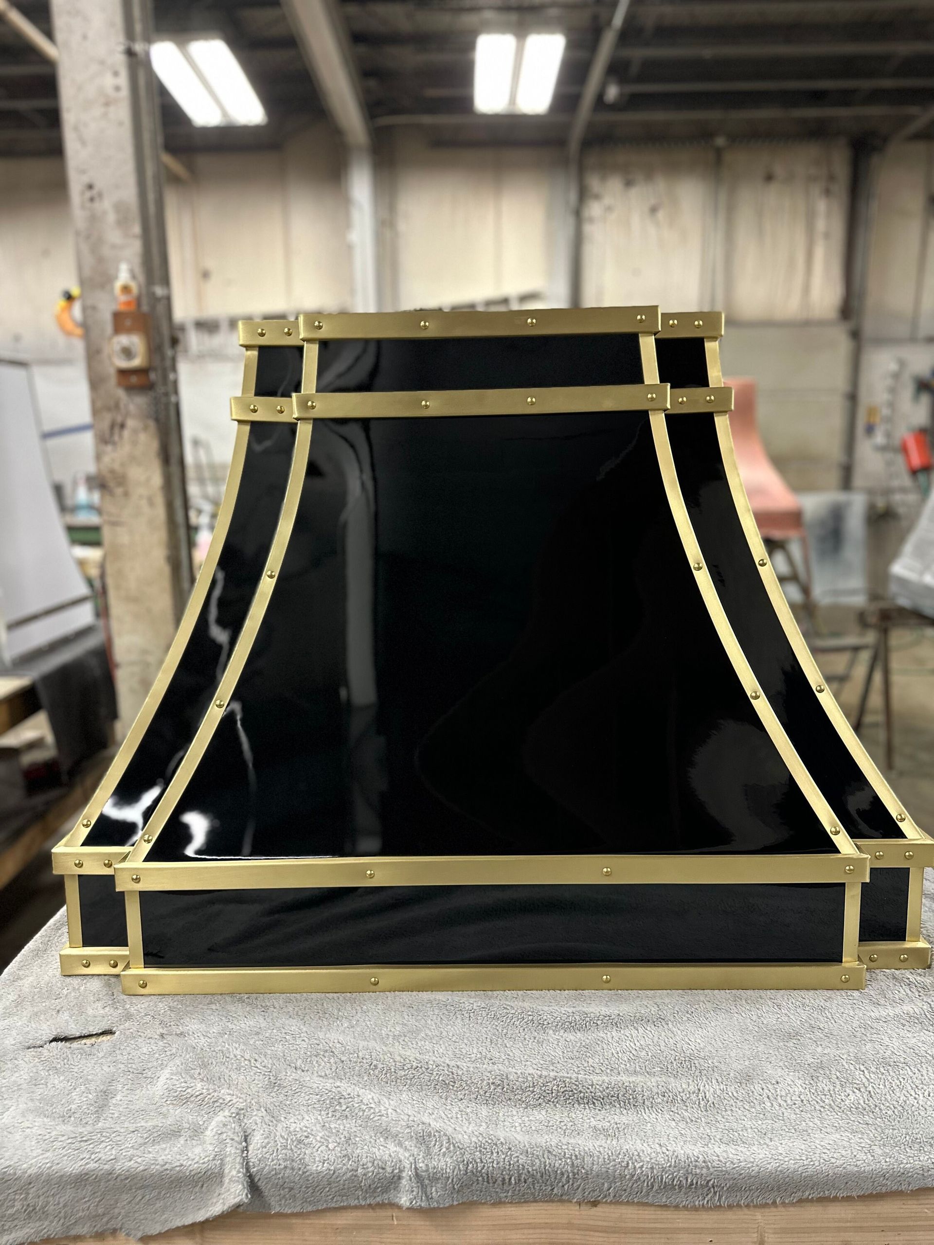 A black lamp shade with gold trim is sitting on a table.