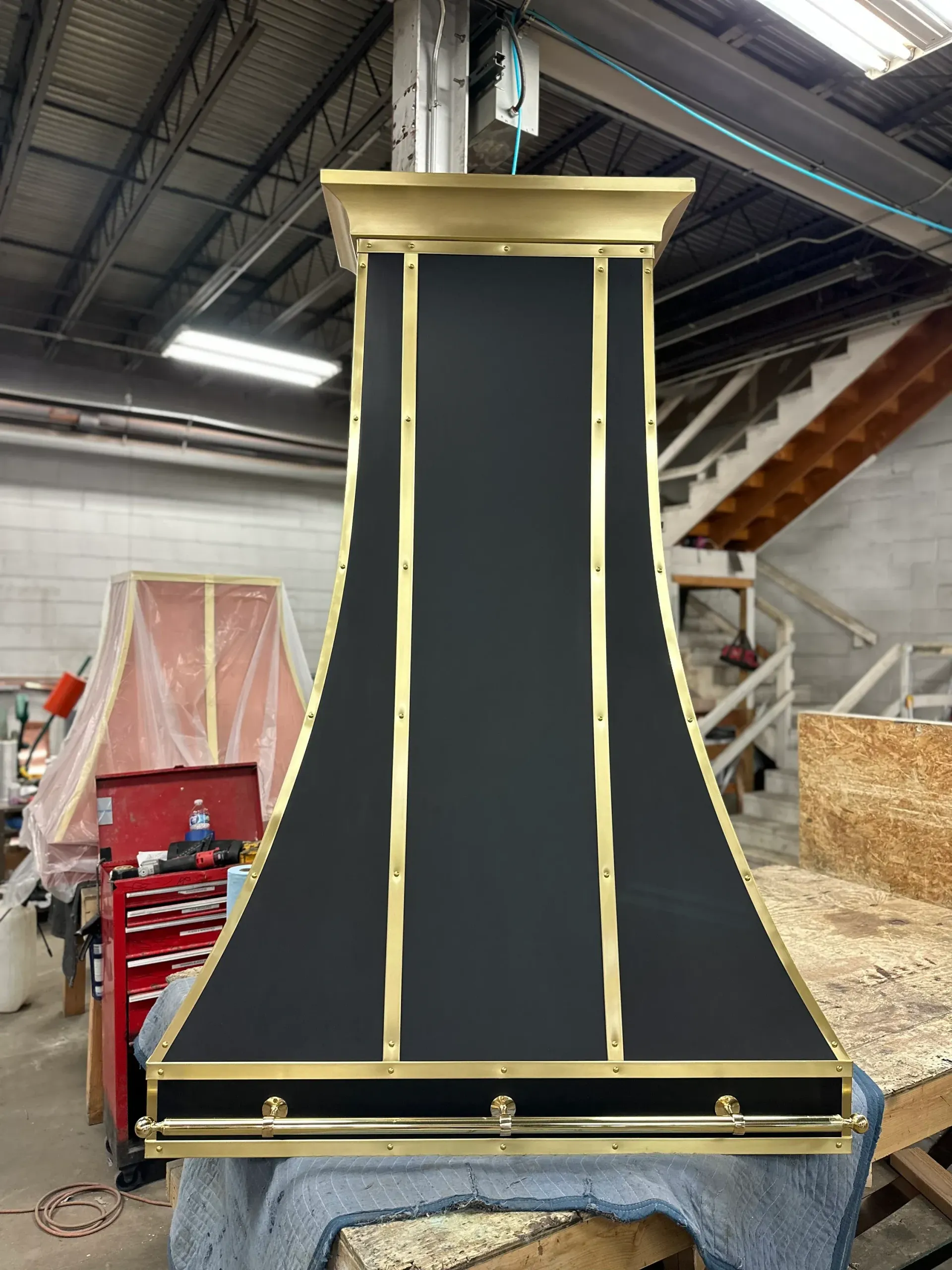 A black and gold hood is sitting on a table in a warehouse.