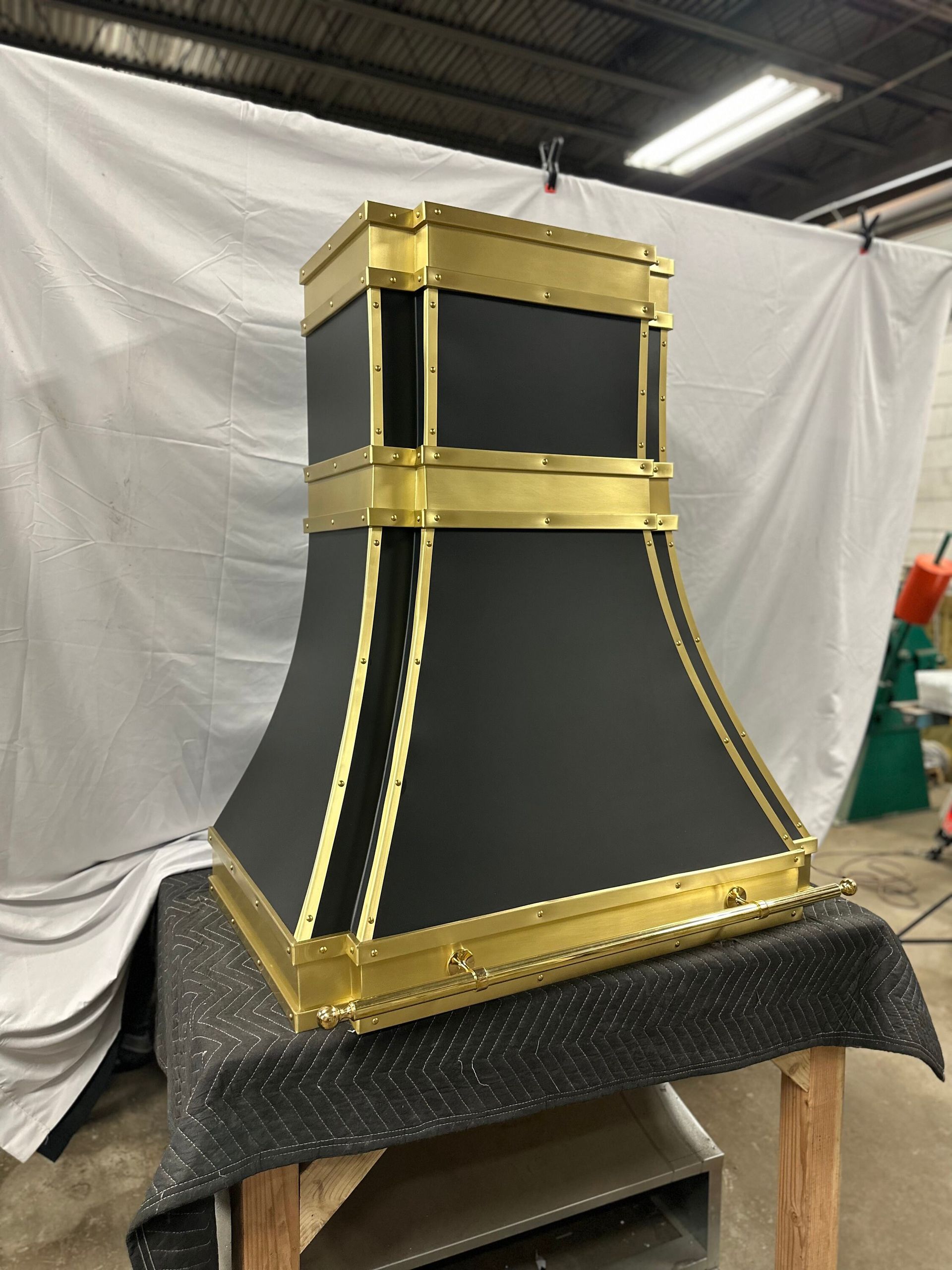 A black and gold hood is sitting on top of a wooden table.