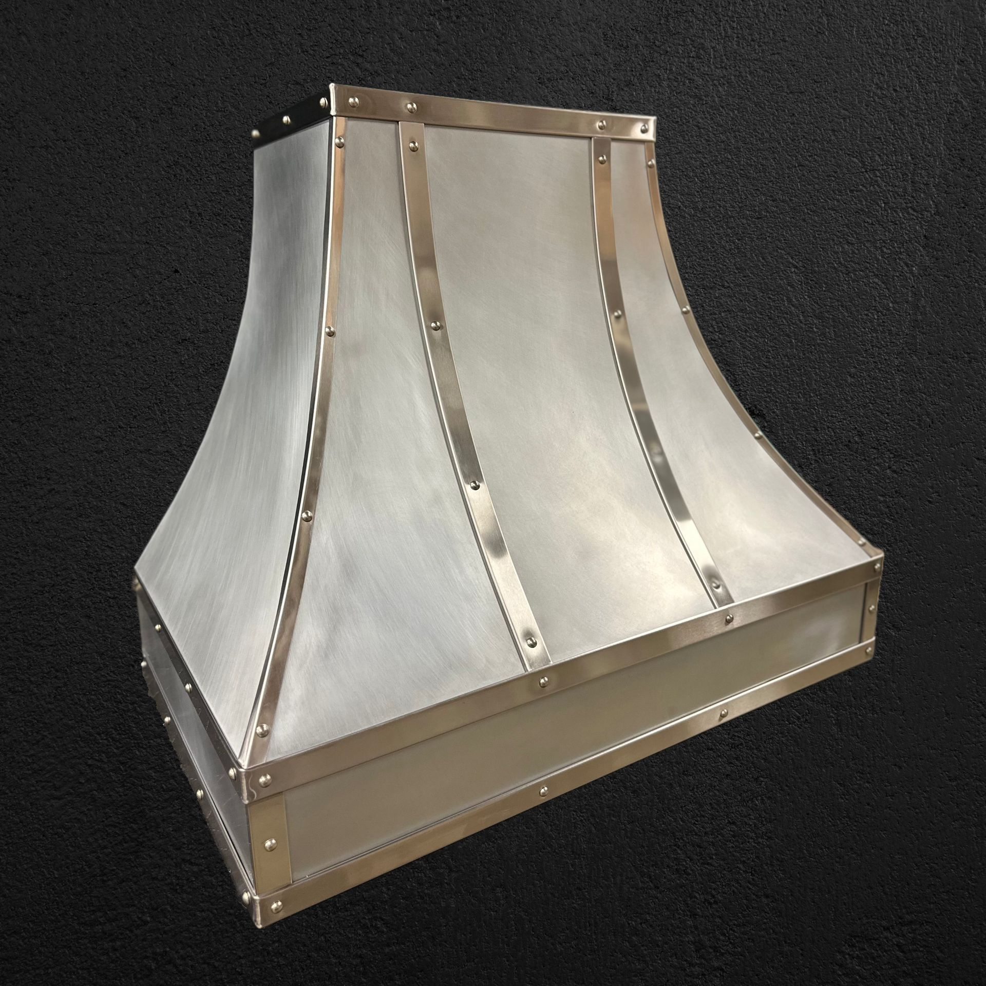 A stainless steel hood is sitting on a black surface