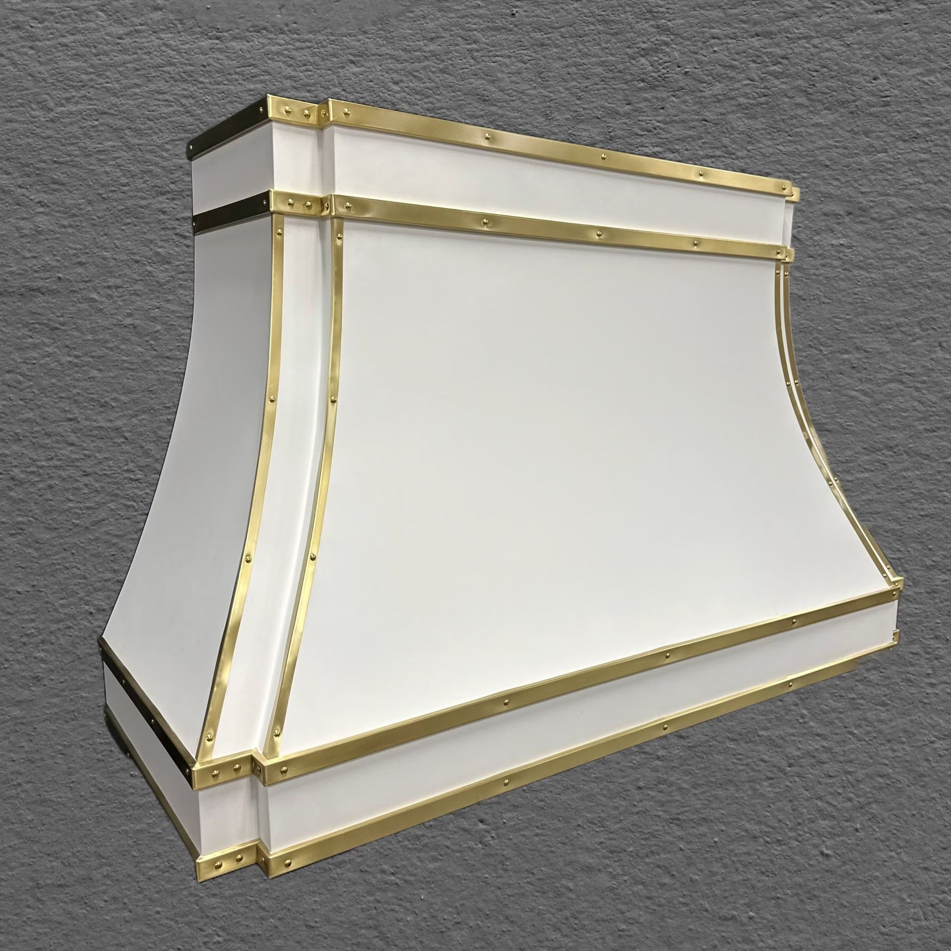 A white lamp shade with gold trim is sitting on a gray surface.