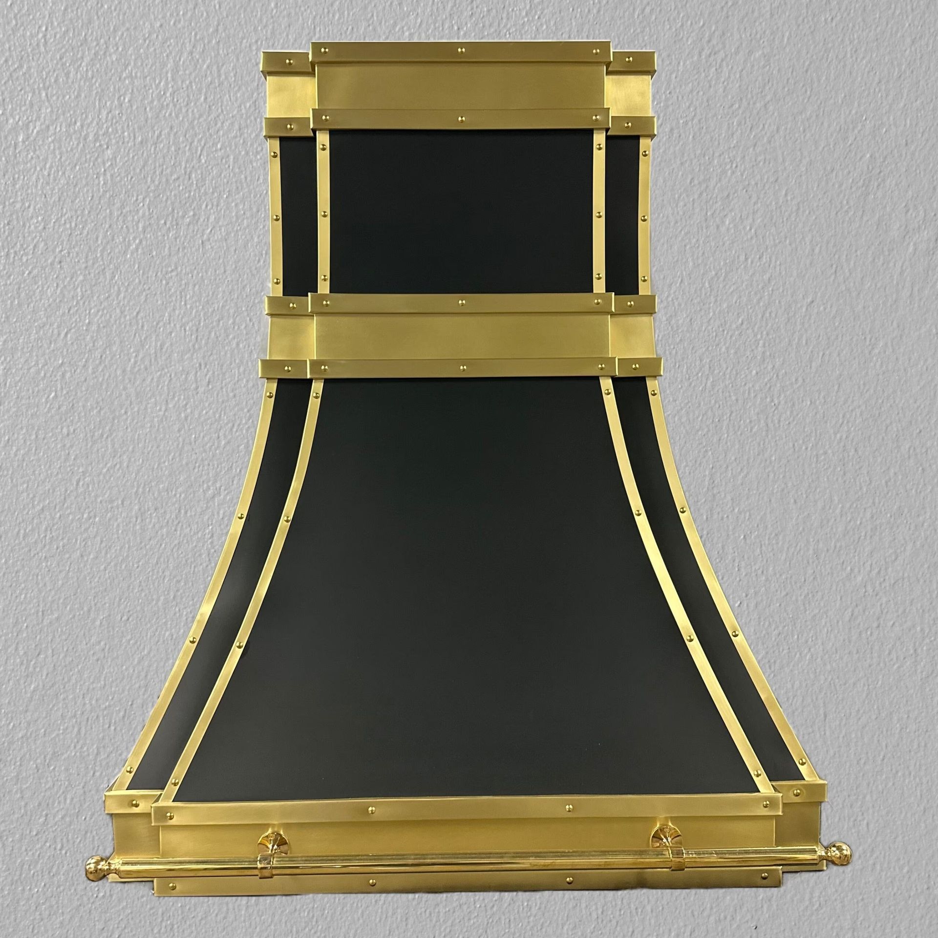 A black and gold hood is hanging on a wall