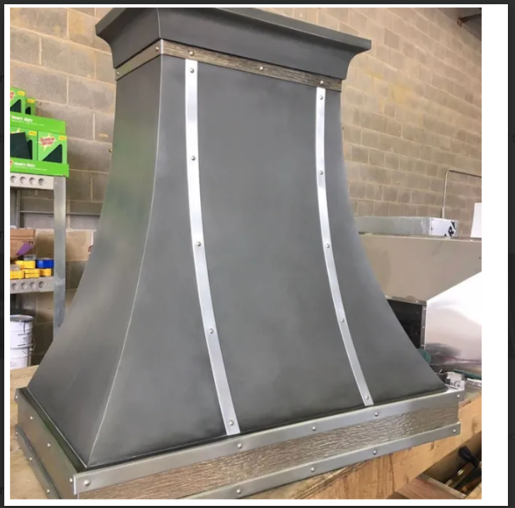 A metal hood is sitting on top of a wooden table.