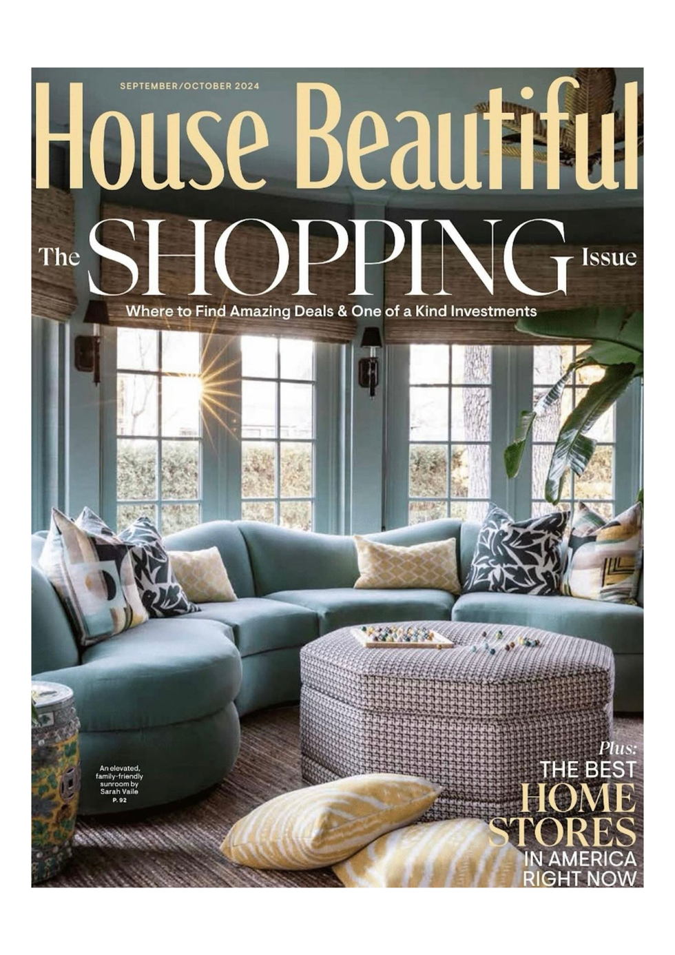 A living room with a blue sectional couch and an ottoman on the cover of a house beautiful magazine.