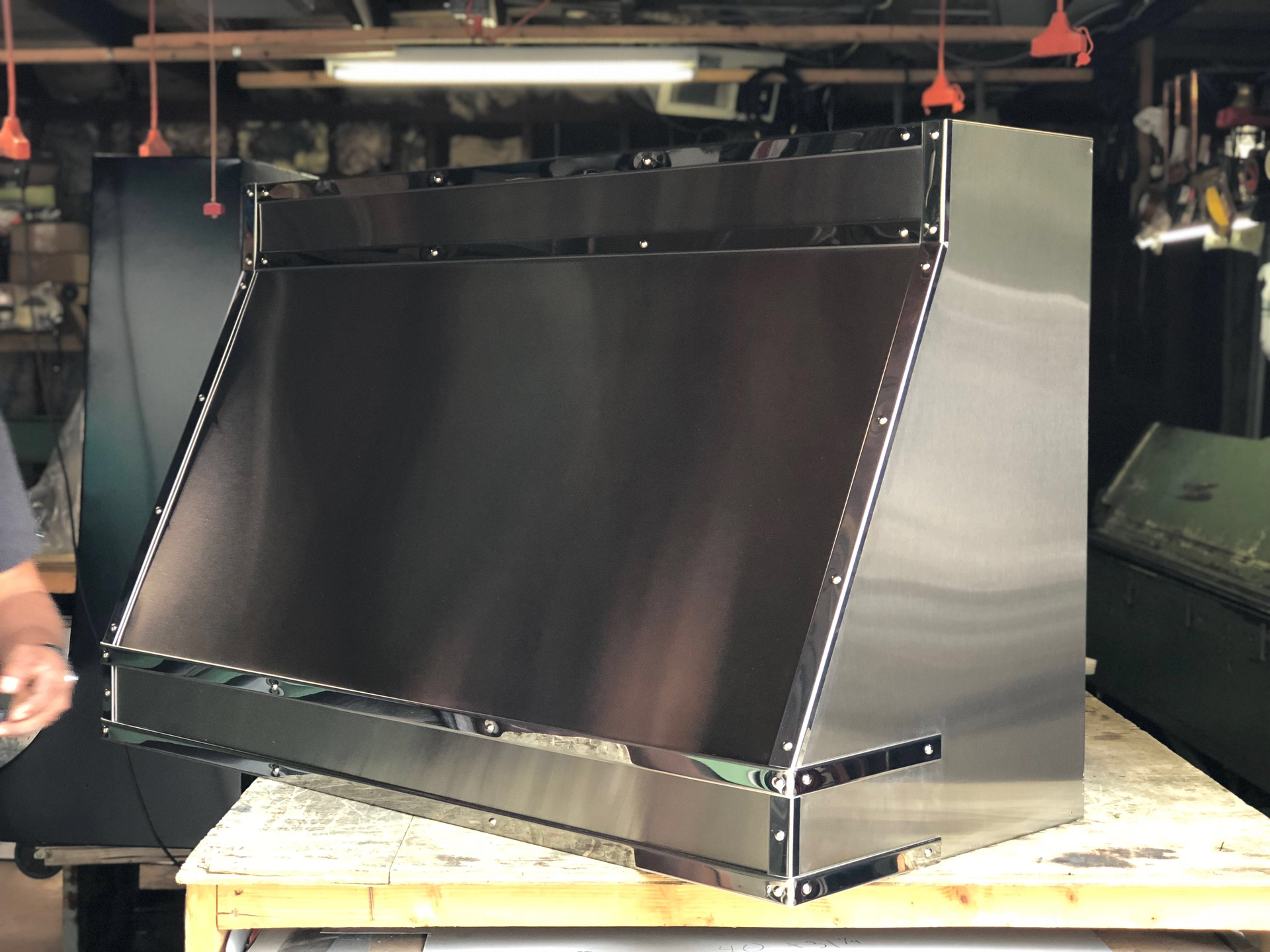 A stainless steel hood is sitting on top of a wooden table.