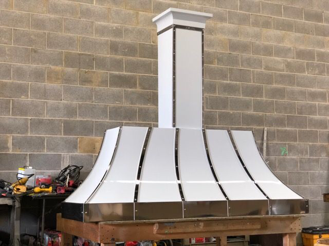 A white stove hood with a brick wall in the background