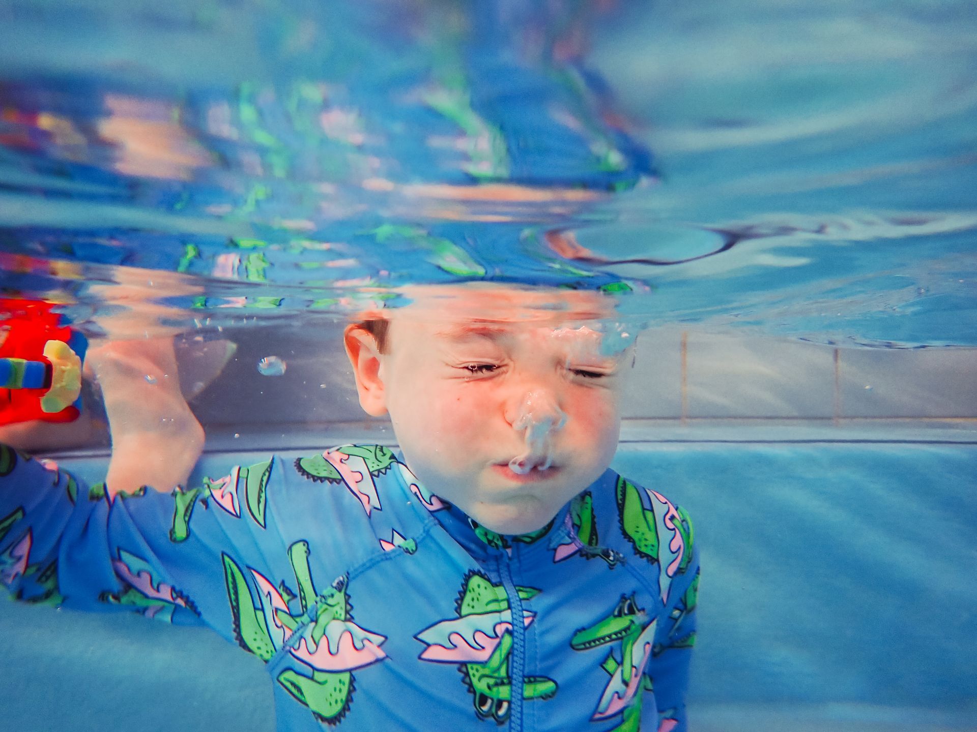 A young boy is swimming underwater in a pool.