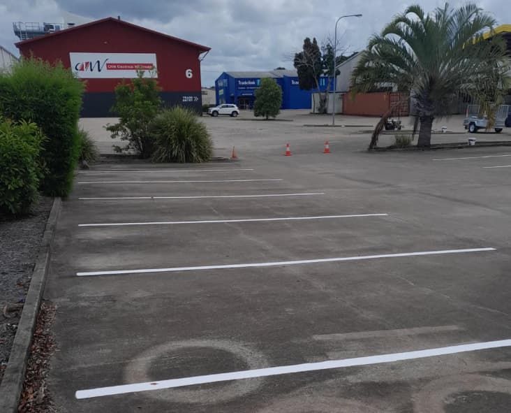 A Parking Lot With A Red Building In The Background — Wide Bay Line Marking in Wondunna, QLD