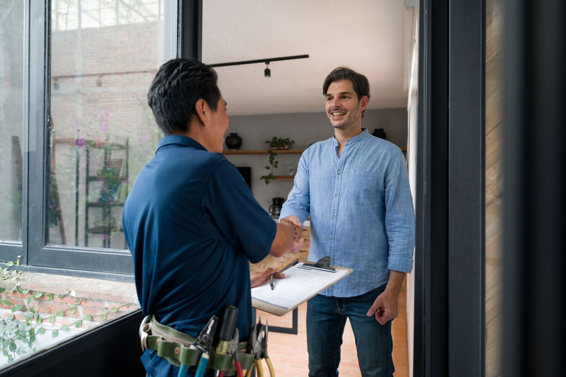 Handyman shaking hands with a homeowner inside a house