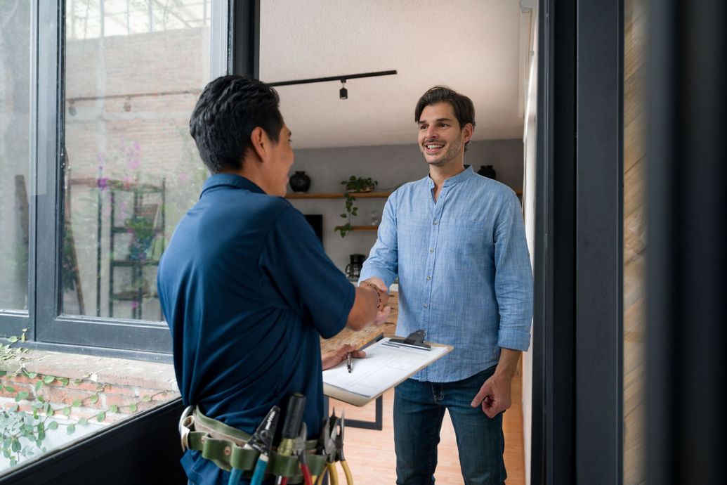 Handyman shaking hands with a homeowner inside a house