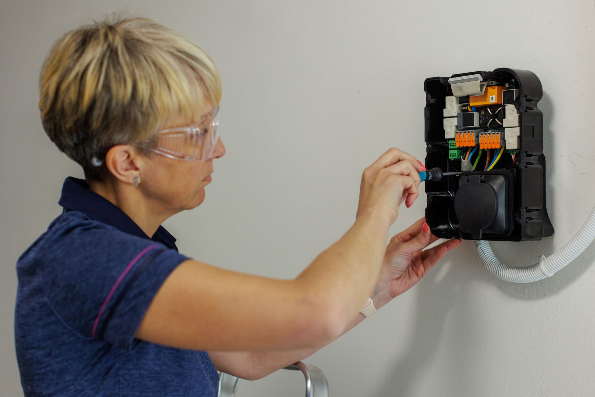 An electrician installing an electric vehicle charger component on a wall