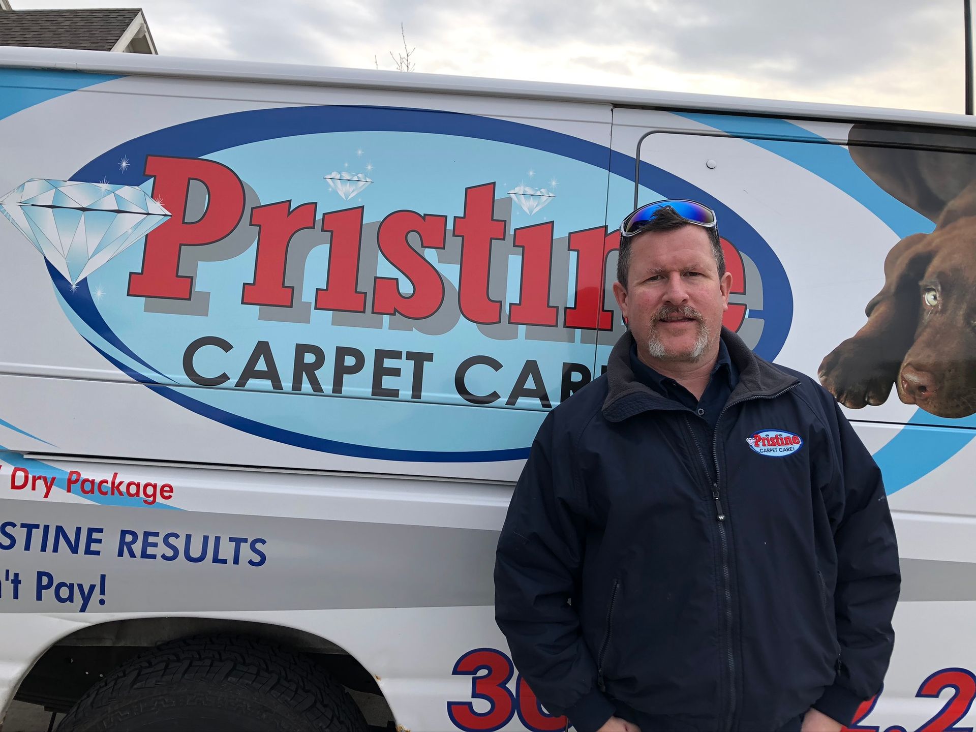A man is standing in front of a pristine carpet company van