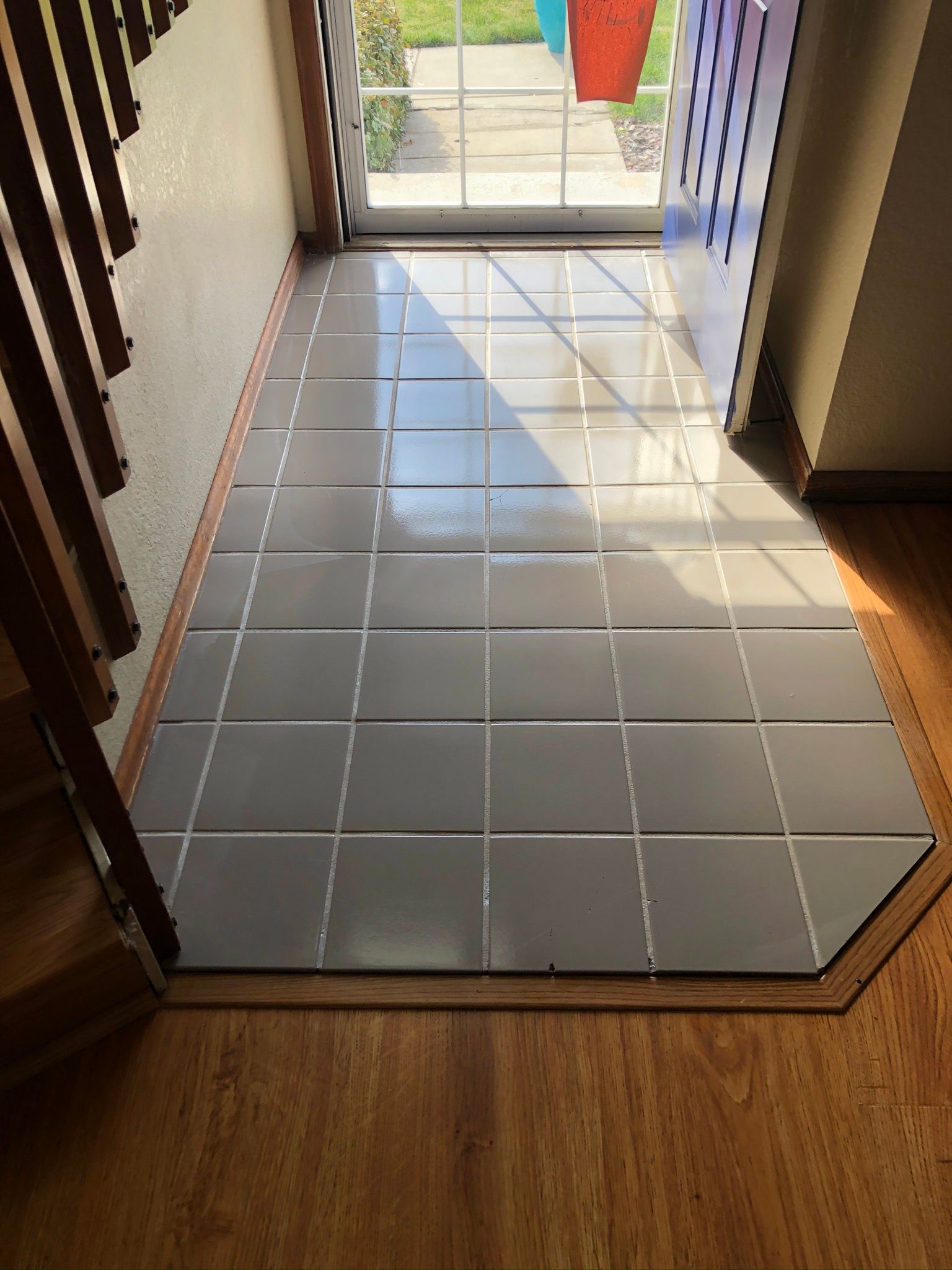 A tiled floor in a hallway next to a staircase