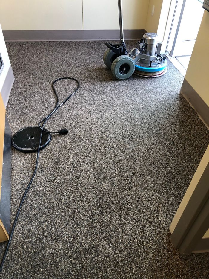 A vacuum cleaner is sitting on a carpeted floor in a room.