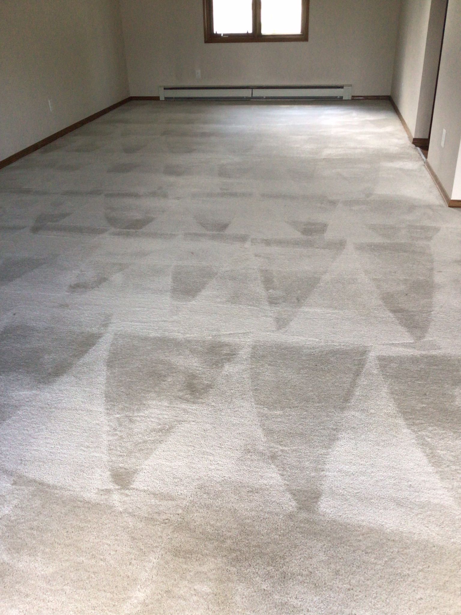A living room with a carpeted floor and a window.
