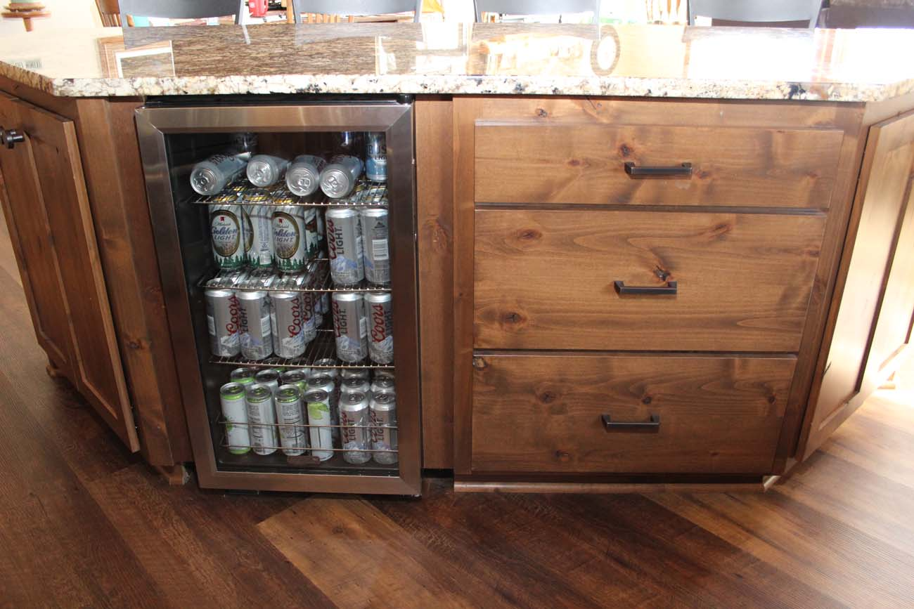 A refrigerator filled with cans and bottles of beer in a kitchen.