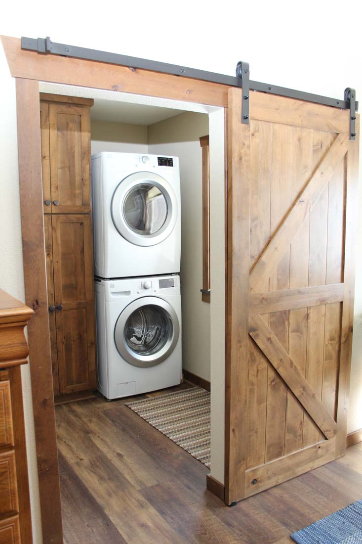 A laundry room with a sliding barn door and a washer and dryer stacked on top of each other.