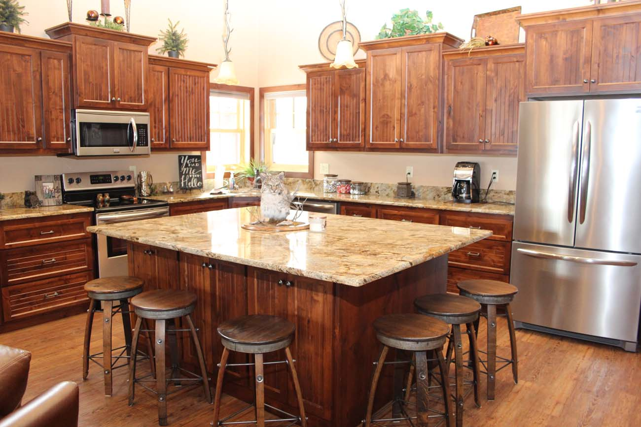 A kitchen with wooden cabinets , granite counter tops , stainless steel appliances and a large island.