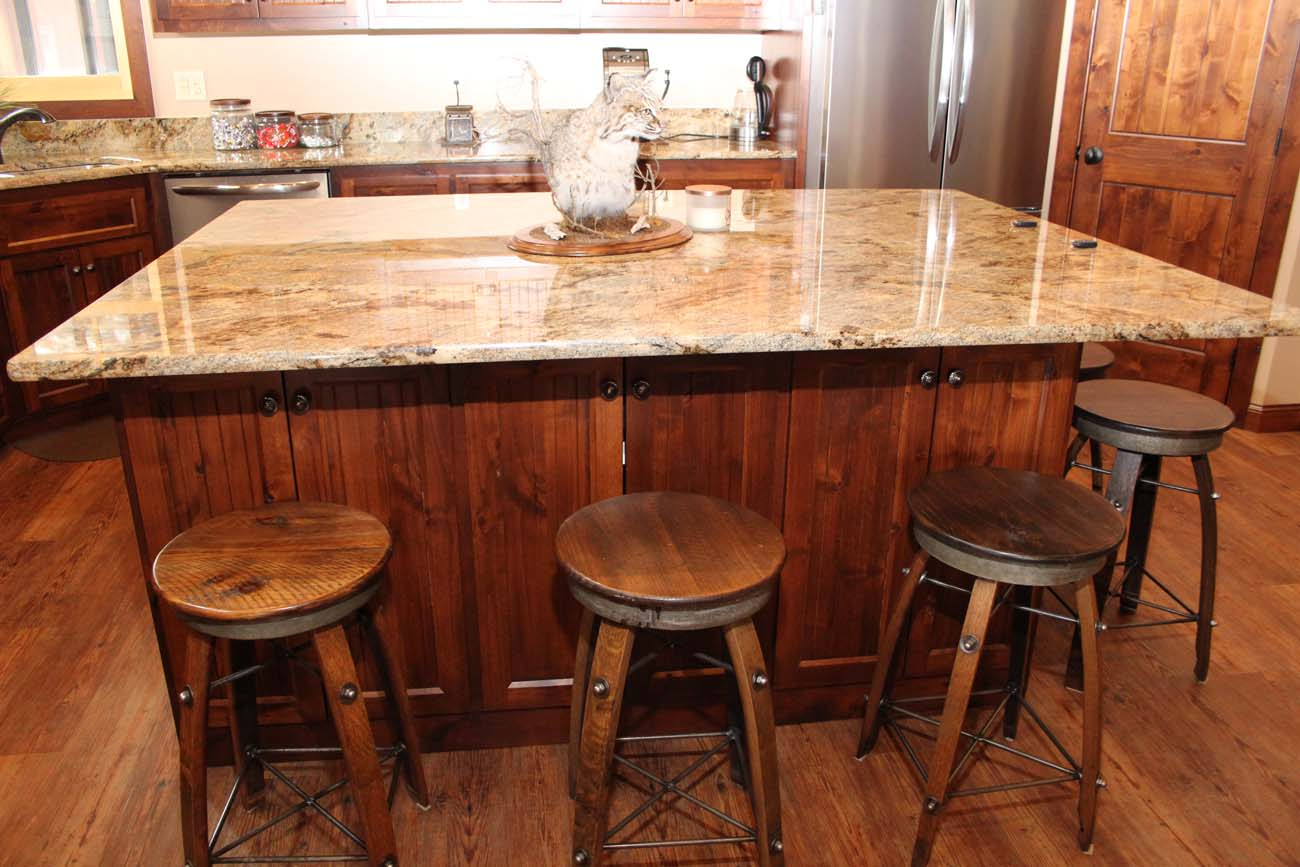 A kitchen with a large island and three stools.