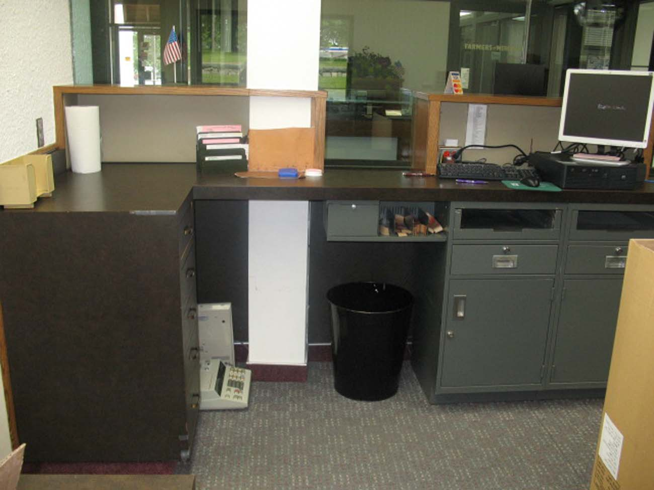 A desk with a computer and a trash can on it