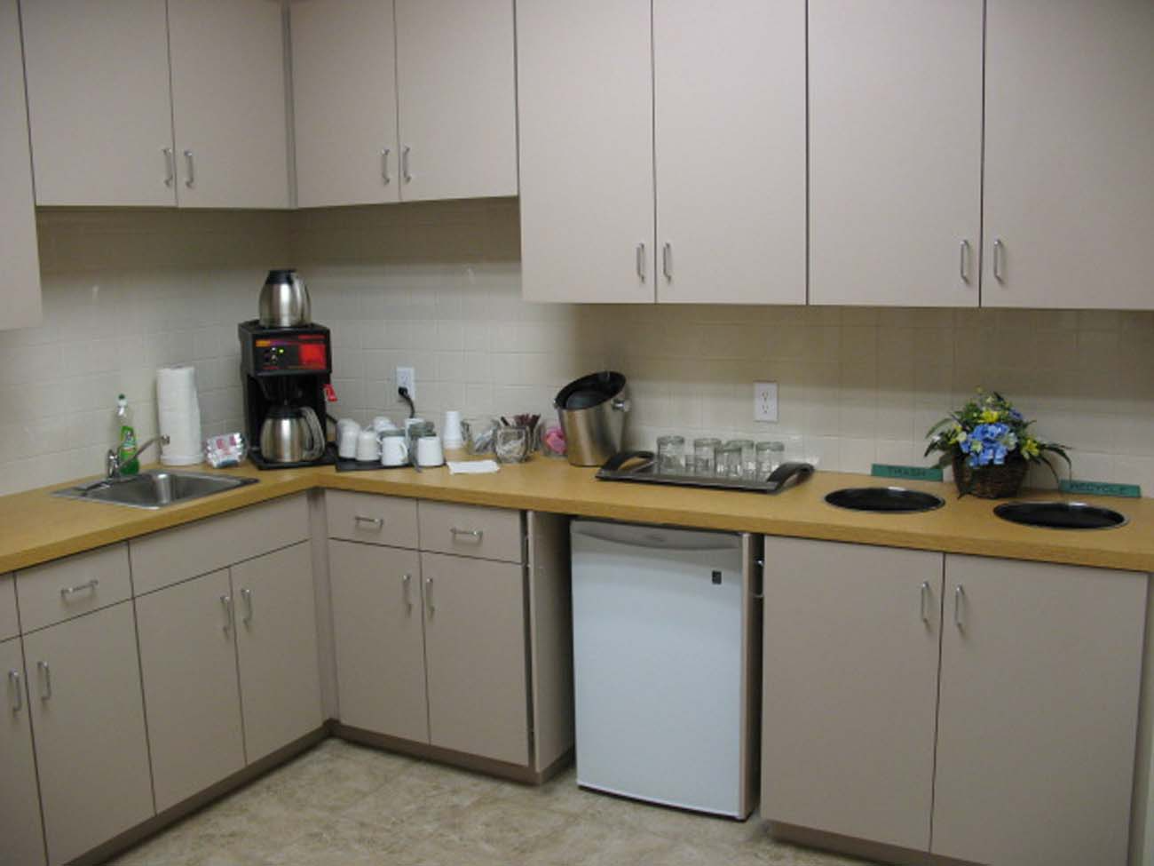 A kitchen with a sink , dishwasher , and coffee maker