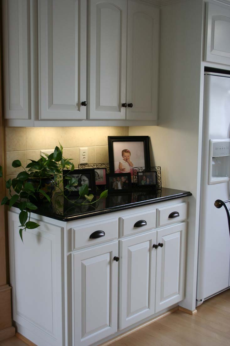 A kitchen with white cabinets and black counter tops
