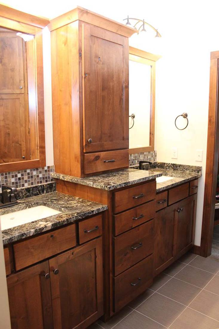 A bathroom with two sinks , two mirrors , and wooden cabinets.