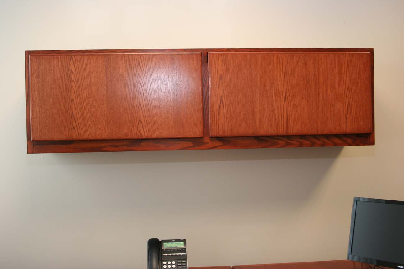 A phone is sitting on a desk next to a wooden cabinet.