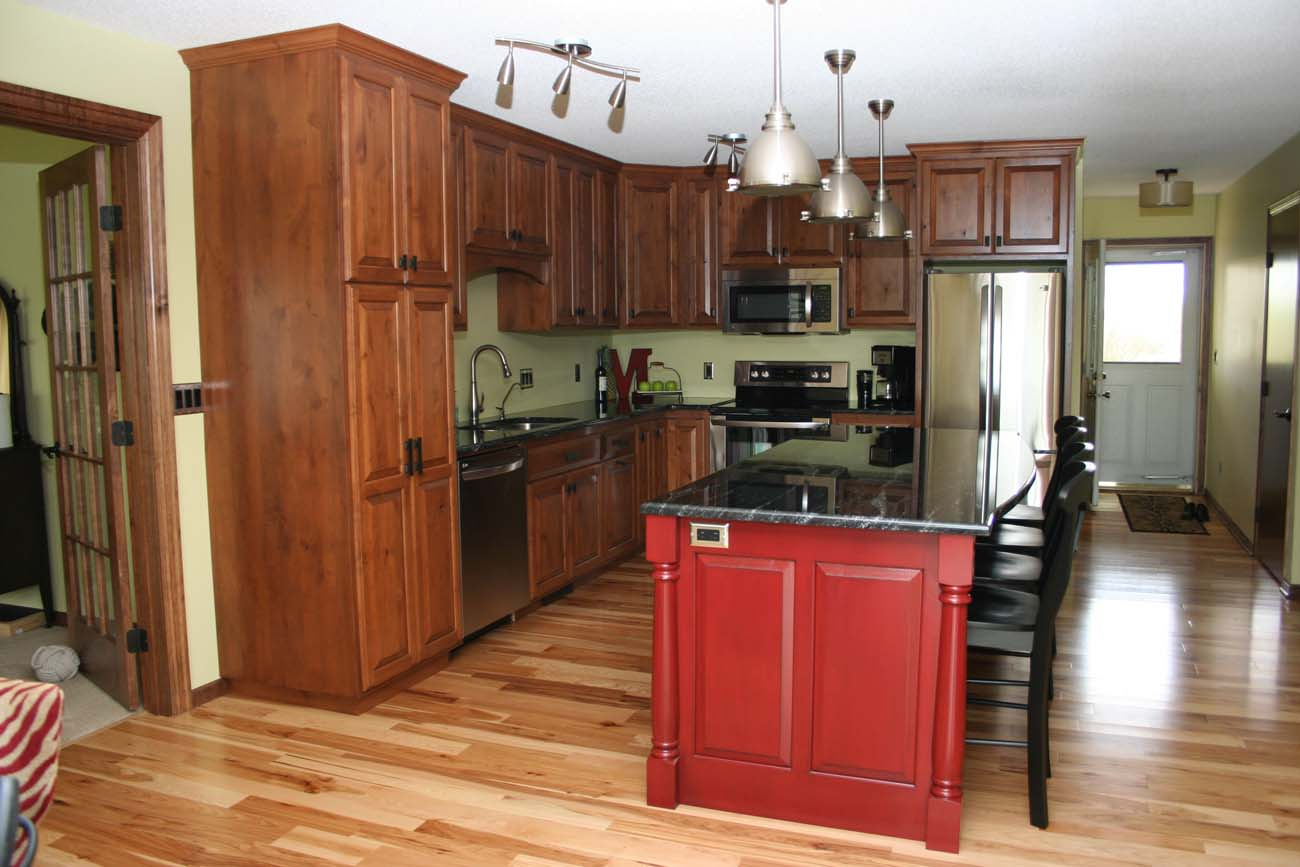 A kitchen with wooden cabinets and a red island