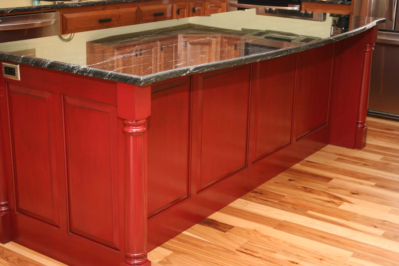 A kitchen with red cabinets and a granite counter top