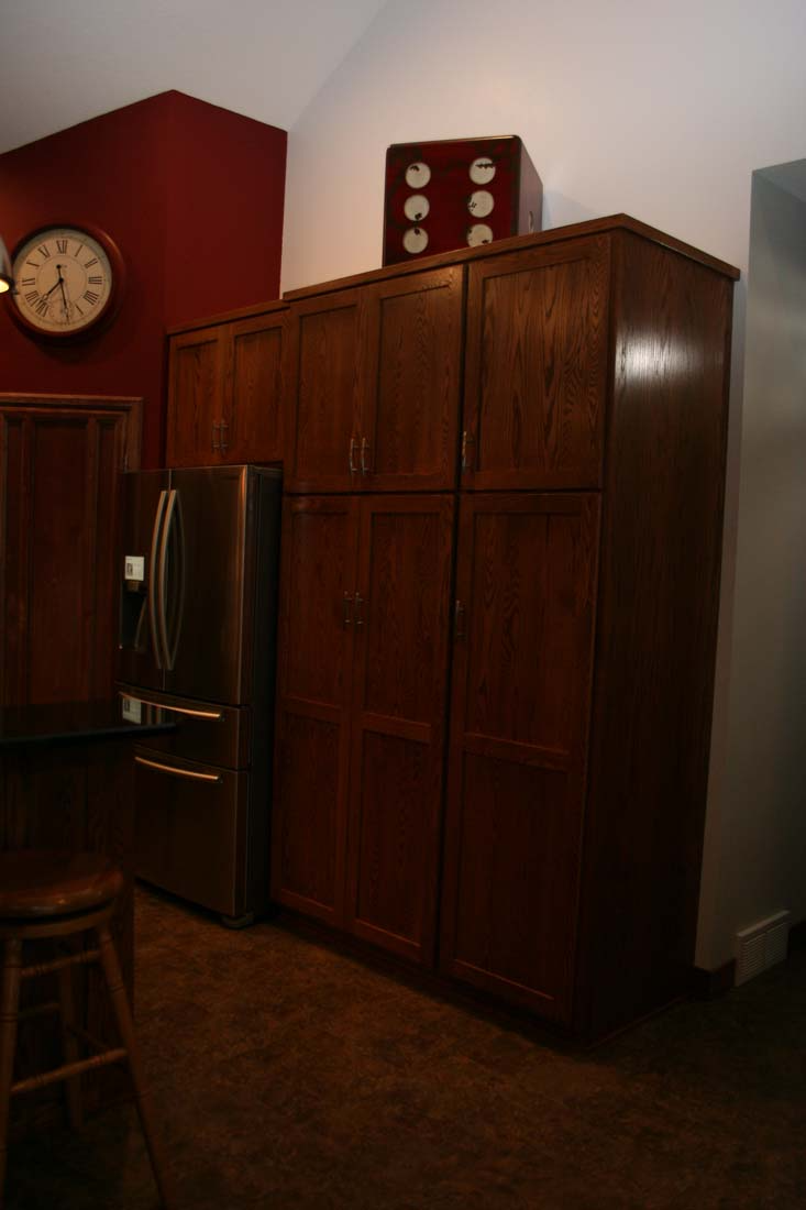 A kitchen with wooden cabinets and a clock on the wall