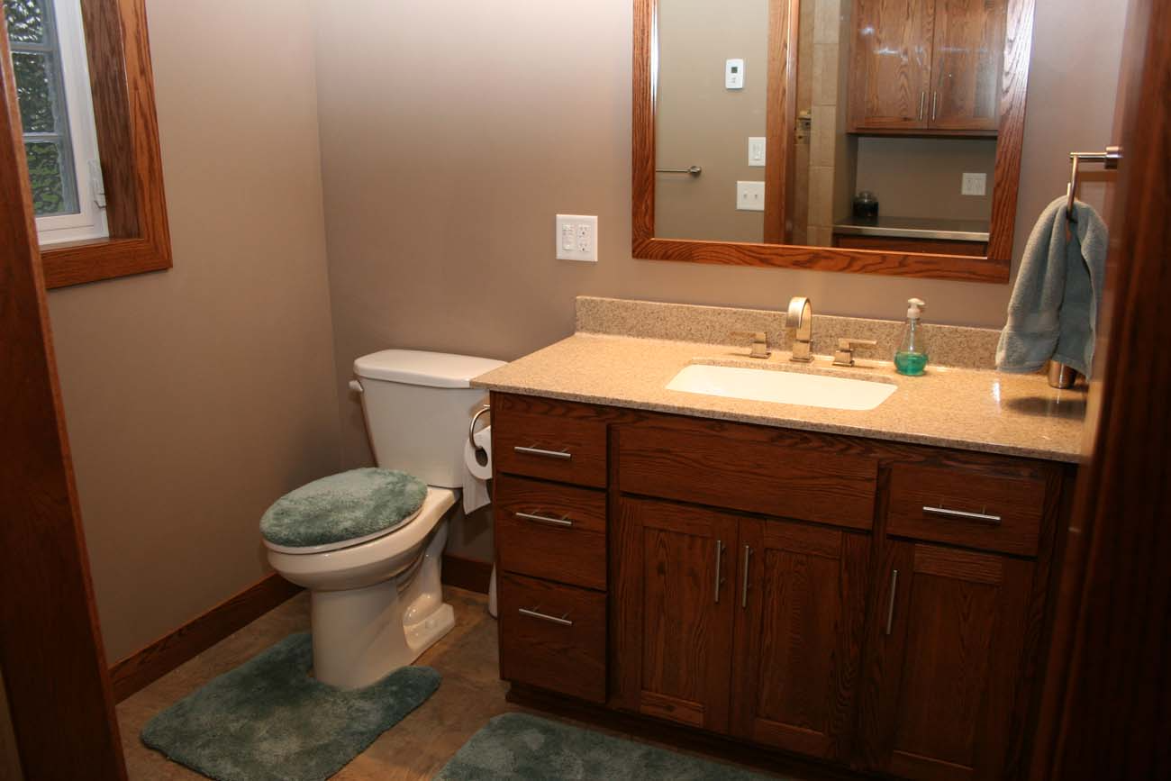 A bathroom with a toilet , sink and mirror.
