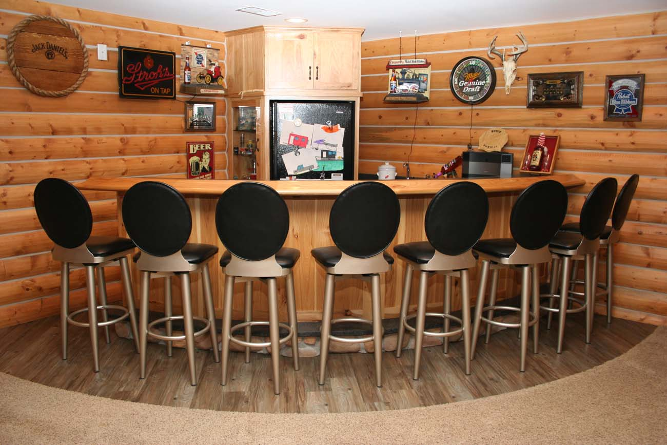 A bar in a log cabin with black stools