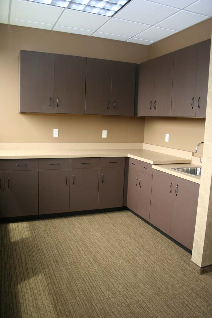 An empty kitchen with brown cabinets and a sink