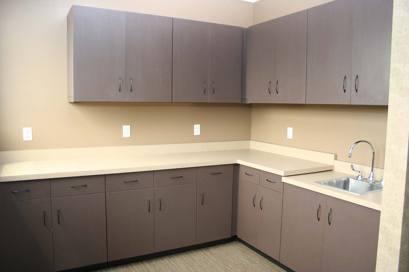 An empty kitchen with gray cabinets and a sink
