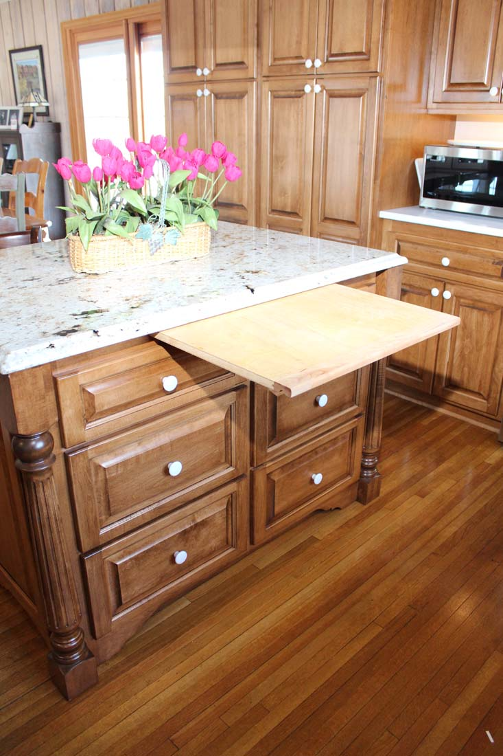 A kitchen island with drawers and a cutting board on top of it.